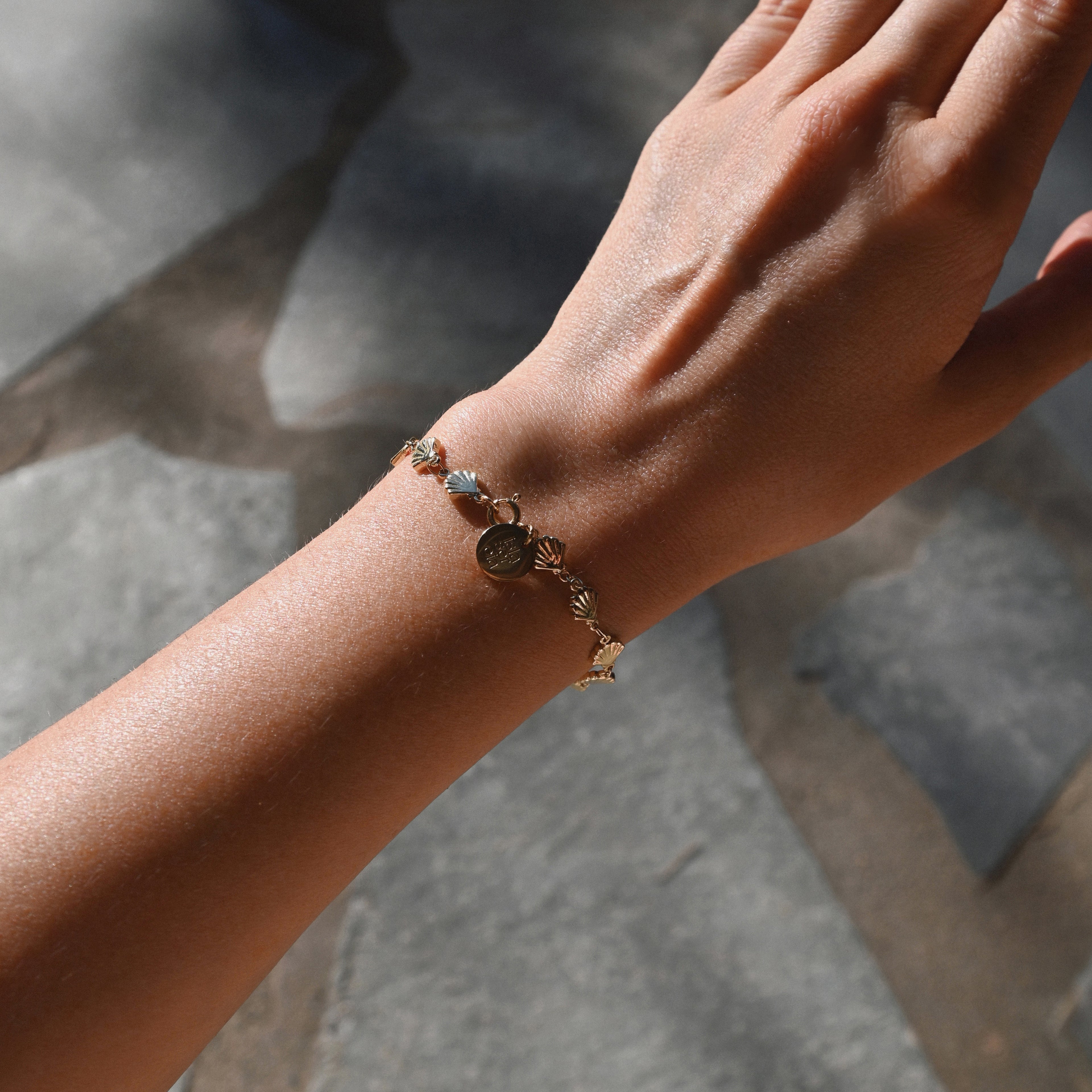 Close-up of a hand wearing a bracelet on a stone surface