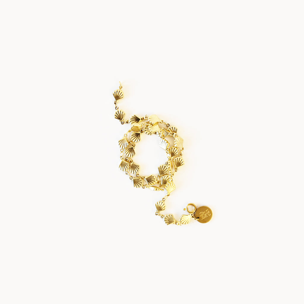 Gold bracelet with shell-like patterns on a white background